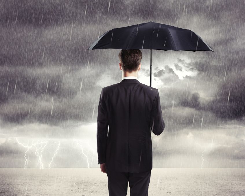 Man in business suit holding umbrella in lightning storm and looking at horizon