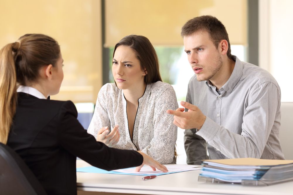 A couple dubiously discusses their claim with an insurance agent.